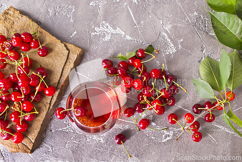 Image of Cherry juice in a transparent glass and fresh cherries