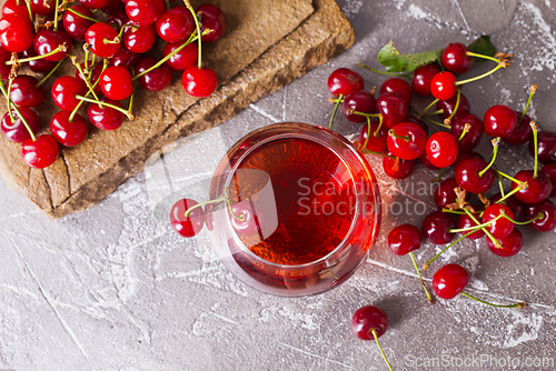 Image of Cherry juice in a transparent glass and fresh cherries