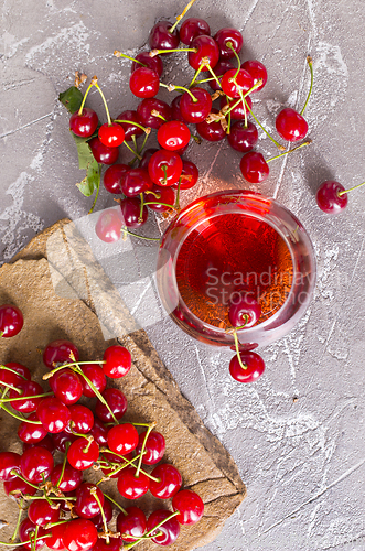 Image of Cherry juice in a transparent glass and fresh cherries