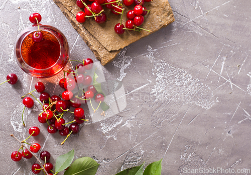Image of Cherry juice in a transparent glass and fresh cherries