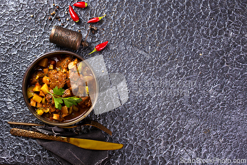 Image of Summer Vegetable spicy stew of zucchini, potatoes, peppers, onions, tomatoes and eggplant in a bowl on the table.