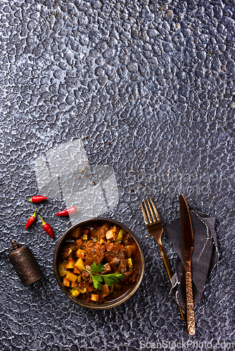Image of Summer Vegetable spicy stew of zucchini, potatoes, peppers, onions, tomatoes and eggplant in a bowl on the table.