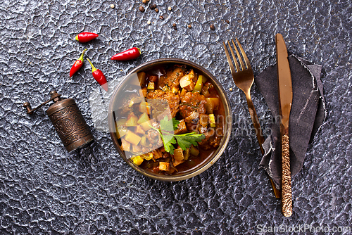 Image of Summer Vegetable spicy stew of zucchini, potatoes, peppers, onions, tomatoes and eggplant in a bowl on the table.