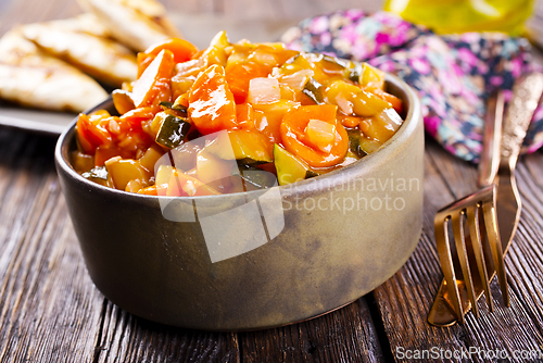 Image of Summer Vegetable spicy stew of zucchini, potatoes, peppers, onions, tomatoes and eggplant in a bowl on the table.
