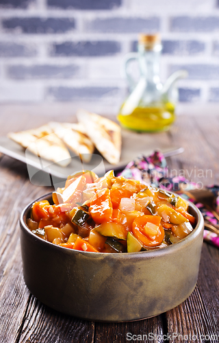 Image of Summer Vegetable spicy stew of zucchini, potatoes, peppers, onions, tomatoes and eggplant in a bowl on the table.