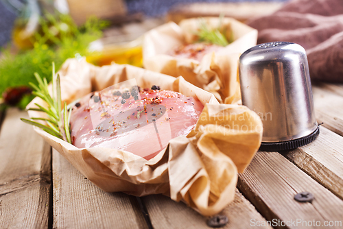 Image of Fresh chicken breast fillet on a wooden cutting board with spices, dark rustic background.