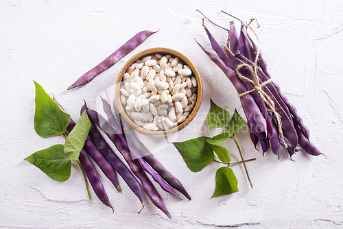 Image of Uncooked dried white haricot beans in bowl n on table. Heap of legume haricot bean background