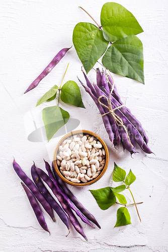 Image of Uncooked dried white haricot beans in bowl n on table. Heap of legume haricot bean background
