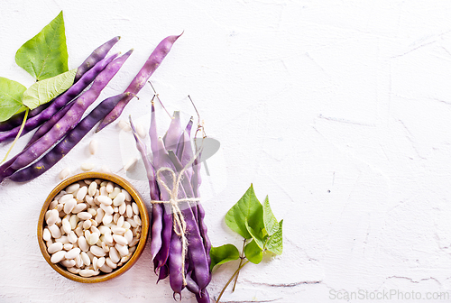 Image of Uncooked dried white haricot beans in bowl n on table. Heap of legume haricot bean background