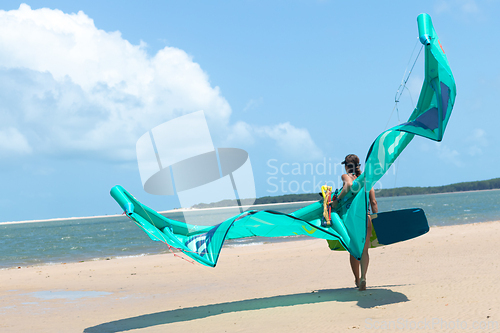 Image of Sexy kitesurfing girl walking on sandy beach holding kite and kiteboard.