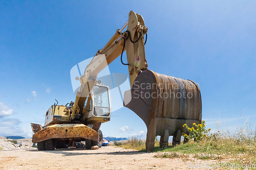 Image of Low angle photo of large excavator on construction site on a sunny day with blue sky.