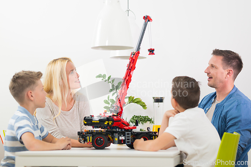 Image of Happy young family playing with toys at dining table at bright modern home.