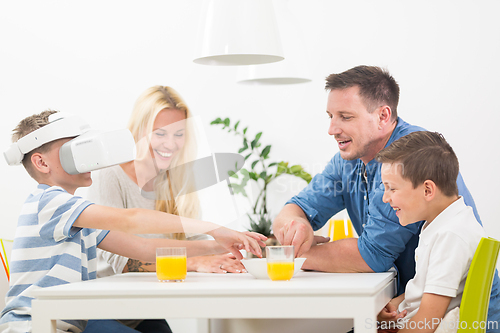 Image of Happy family at home on living room sofa having fun playing games using virtual reality headset
