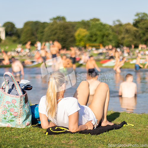 Image of People enjoying the summer, sunbathing, swimming in river Izar and relaxing on green of the Englischer Garten in Munich, Germany on a sunny summer holiday day.