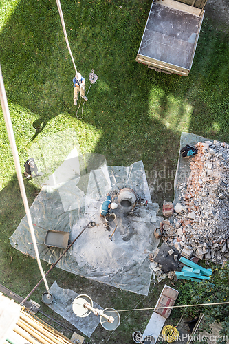 Image of Top view of authentic builder men working with shovel during concrete cement solution mortar preparation in mixer at construction site
