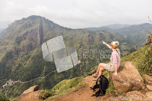 Image of Active caucasian blonde woman enjoing fresh air and pristine nature while tracking among tea plantaitons near Ella, Sri Lanka. Bacpecking outdoors tourist adventure