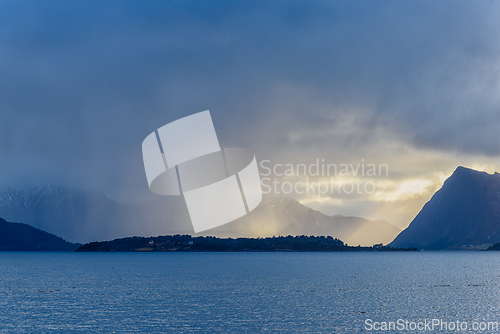 Image of Majestic mountains and serene waters under a cloudy sky at dusk 
