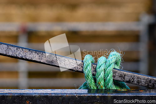 Image of Rope securing a metal pole against a blurred industrial backgrou