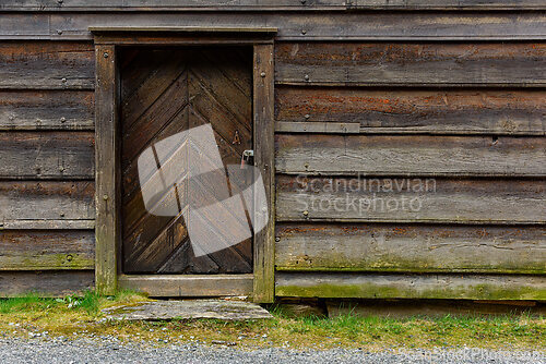 Image of Weathered wooden door with chevron pattern set against a rustic 