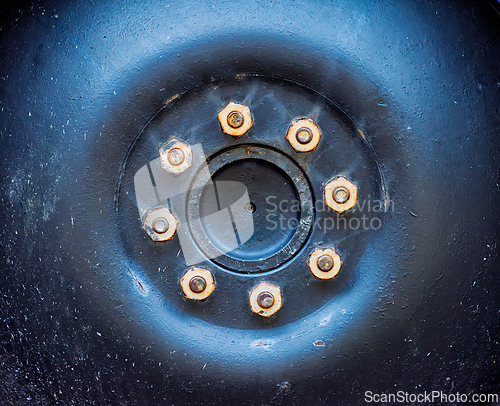 Image of Close-up view of a metal wheel hub with bolts against a black ba