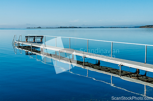 Image of Tranquil lake view with a pier extending into calm water under c