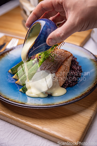 Image of Chef pouring sauce on salmon steak