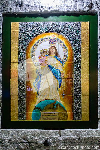Image of Religious artwork and statues on the textured stone walls of the Salt Cathedral of Zipaquira, Colombia.