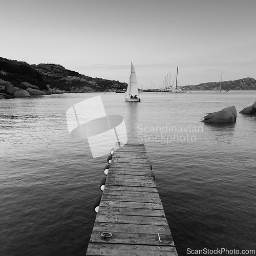 Image of Wooden pier and sailboats sailing in evening calm sea of marvellous Porto Rafael, Costa Smeralda, Sardinia, Italy. Symbol for relaxation, wealth, leisure activity