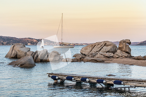 Image of Sailboat sailing by beautiful rocky formations on the Spiaggia di Punta Nera beach. Luxury summer adventure, active vacation in Mediterranean sea, Costa Smeralda, Sardinia, Italy