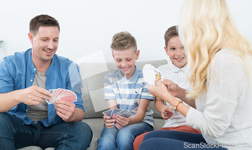 Image of Happy young family playing card game at home.