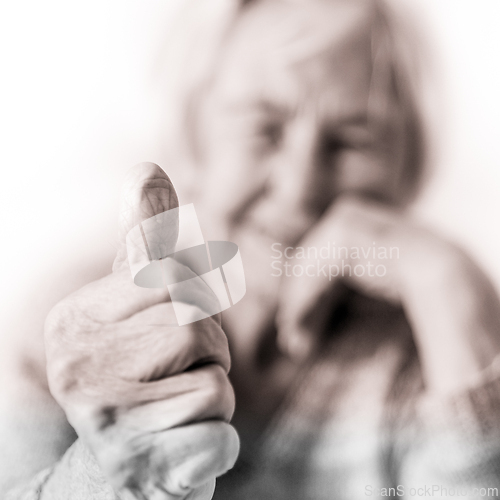 Image of Happy 96 years old elderly woman giving a thumb up and looking at camera.