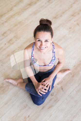 Image of Fit sporty active girl in fashion sportswear sitting on the floor in yoga studio. Active urban lifestyle