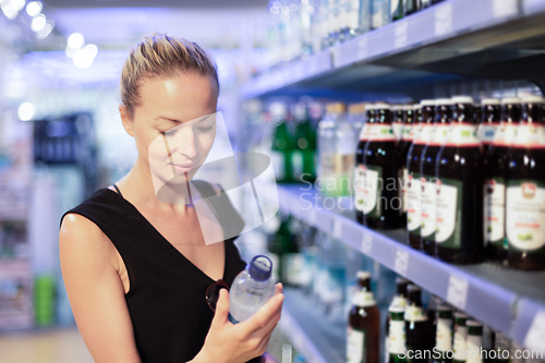 Image of Woman choosing mineral water in grocery store.