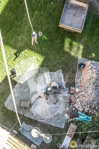Image of Top view of authentic builder men working with shovel during concrete cement solution mortar preparation in mixer at construction site