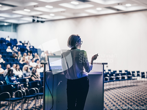 Image of Female speaker giving a talk on corporate business conference. Unrecognizable people in audience at conference hall. Business and Entrepreneurship event.