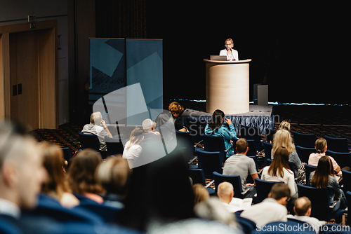Image of Female speaker giving a talk on corporate business conference. Unrecognizable people in audience at conference hall. Business and Entrepreneurship event.