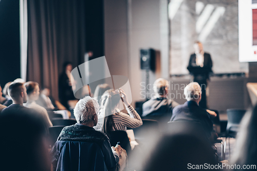 Image of Speaker giving a talk in conference hall at business event. Rear view of unrecognizable people in audience at the conference hall. Business and entrepreneurship concept.