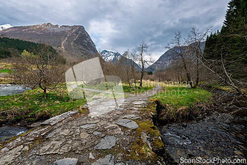 Image of Breathtaking view of a mountain path in a valley under a moody s