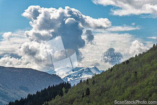 Image of Majestic snow-capped mountains beneath a dramatic cloud-filled s