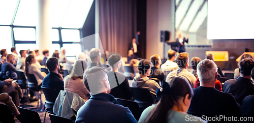 Image of Speaker giving a talk in conference hall at business event. Rear view of unrecognizable people in audience at the conference hall. Business and entrepreneurship concept.