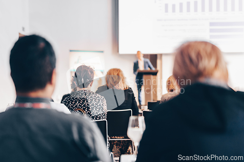 Image of Speaker giving a talk in conference hall at business event. Rear view of unrecognizable people in audience at the conference hall. Business and entrepreneurship concept.