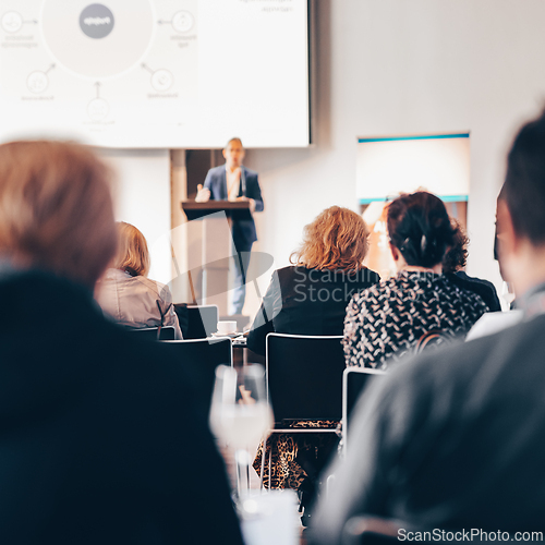 Image of Speaker giving a talk in conference hall at business event. Rear view of unrecognizable people in audience at the conference hall. Business and entrepreneurship concept.