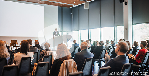 Image of Speaker giving a talk in conference hall at business event. Rear view of unrecognizable people in audience at the conference hall. Business and entrepreneurship concept.