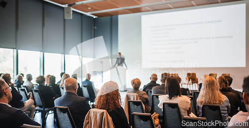 Image of Speaker giving a talk in conference hall at business event. Rear view of unrecognizable people in audience at the conference hall. Business and entrepreneurship concept.
