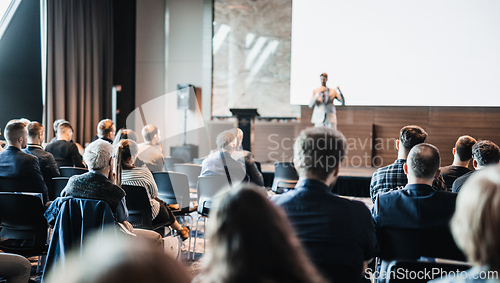 Image of Speaker giving a talk in conference hall at business event. Rear view of unrecognizable people in audience at the conference hall. Business and entrepreneurship concept.