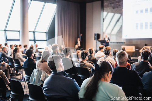 Image of Female speaker giving a talk on corporate business conference. Unrecognizable people in audience at conference hall. Business and Entrepreneurship event.