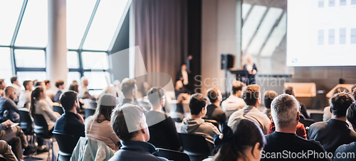 Image of Female speaker giving a talk on corporate business conference. Unrecognizable people in audience at conference hall. Business and Entrepreneurship event.