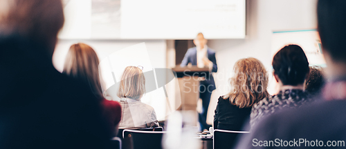 Image of Speaker giving a talk in conference hall at business event. Rear view of unrecognizable people in audience at the conference hall. Business and entrepreneurship concept.