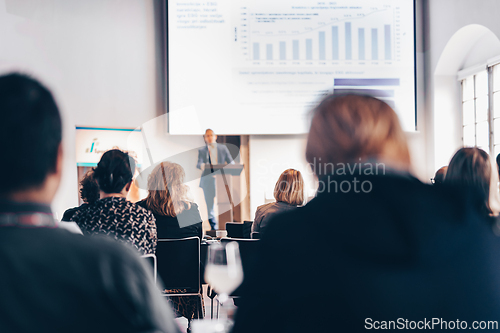 Image of Speaker giving a talk in conference hall at business event. Rear view of unrecognizable people in audience at the conference hall. Business and entrepreneurship concept.