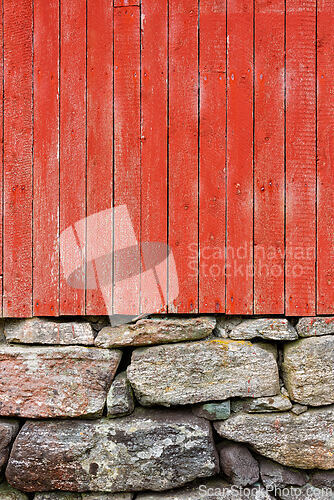 Image of Bright red wooden wall features rustic stone base showcasing a b